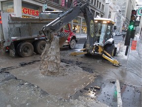 A city worker takes broken asphalt from the site of a broken water main at the corner of Peel and Ste. Catherine Sts. in Montreal Monday, January 4, 2016. (John Kenney / MONTREAL GAZETTE)