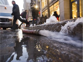 A man jumps over a hose draining water from a broken water main at the corner of Peel and Ste. Catherine Sts. in Montreal in 2016.