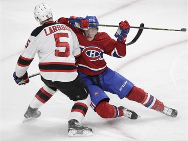 Daniel Carr of the Montreal Canadiens is checked by defensemen Adam Larsson of the New Jersey Devils in the first period of at the Bell Centre in Montreal Wednesday, Jan. 6, 2016.
