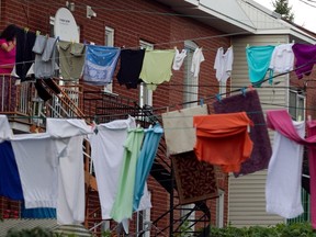 A woman takes in her laundry before the rain in the Park Ex district of Montreal on Wednesday, September 11, 2013.