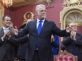Quebec Premier Philippe Couillard stands in front of his new cabinet, during a ceremony, Thursday, Jan. 28, 2016 at the legislature in Quebec City. Caucus president Nicole Ménard, from the left, Stéphane Billette, whip, and Quebec Finance Minister Carlos Leitão, right, stand behind.