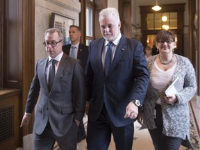 Quebec Premier Philippe Couillard, flanked by staff members Charles Robert, left, and Johanne Whittom, walks to question period, Thursday, Nov. 19, 2015 at the legislature in Quebec City.