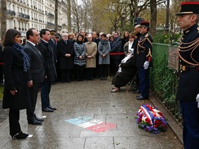 French President Francois Hollande (2ndL), Paris Mayor Anne Hidalgo (L) and Prime Minister Manuel Valls look at a commemorative plaque on Jan. 5, 2016 during a ceremony at the site where a policeman was killed during the last year's January attack in Paris.