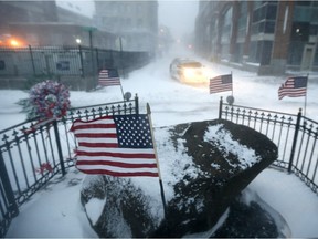 United States flags blow in gusty winds during a snowstorm, Saturday, Jan. 23, 2016, in Hoboken, N.J. Towns across the state are hunkering down during a major snowstorm that hit overnight.