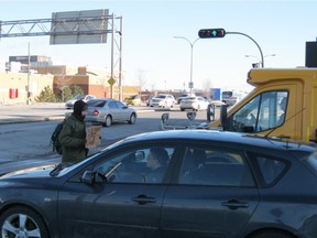 A panhandler solicits donations at St-Jean Blvd. in Pointe-Claire as motorists exit eastbound Highway 40 in the last week of January 2016. (Photo Peter Varga, Special to the Montreal Gazette)