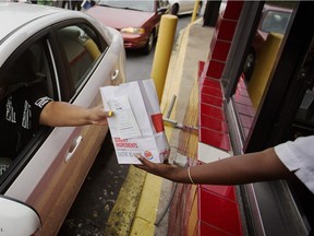 A worker hands a food order over to a customer at a drive-thru restaurant in Atlanta.