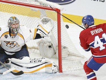 Goalie Pekka Rinne keeps an eye on the puck as Paul Byron tries to knock it down during second- period action on Monday, Feb. 22, at the Bell Centre in Montreal.