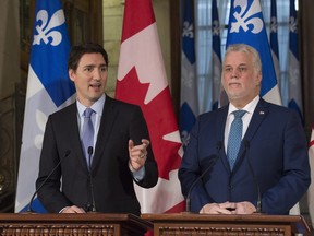 Prime Minister Justin Trudeau responds to reporters' questions at a news conference, while Quebec Premier Philippe Couillard, right, looks on at the Premier's Quebec City office, on Friday, Dec. 11, 2015.