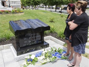 Visitors read a monument to Lac-Mégantic's 47 train disaster victims outside the Ste-Agnès church in the town, Sunday, July , 2014, after a mass to mark the first anniversary of the tragedy.