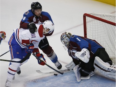 Montreal Canadiens centre Lars Eller, left, front, of Denmark, is held by Colorado Avalanche defenceman Erik Johnson, back left, while trying to shoot the puck at goalie Semyon Varlamov, of Russia, in the first period of an NHL hockey game Wednesday, Feb. 17, 2016, in Denver.