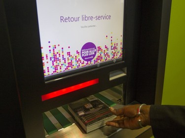 A worker at the N.D.G. Cultural Centre and Benny Library illustrates a self-service return device in Montreal on Saturday, Feb. 6, 2016, at an open house.