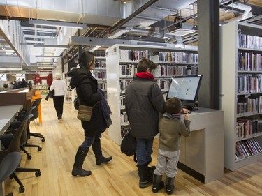 Victor (centre) and Maxime Popovic do a catalogue search as their mother Tina Yang watches at the N.D.G. Cultural Centre and Benny Library in Montreal on Saturday, Feb. 6, 2016, at an open house.