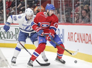 Montreal Canadiens Alex Galchenyuk and Tampa Bay Lightning Nikita Nesterov, left, compete for the loose puck during third period of National Hockey League game in Montreal Tuesday February 9, 2016.