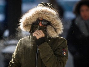 A woman shields her face from the cold on Ste. Catherine St. on a cold winter day in downtown Montreal Feb. 13, 2016.