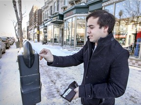 Jason Ghetler puts money in a parking meter on Sherbrooke St. in Westmount, in Montreal Saturday February 13, 2016. Westmount is replacing their meters with a new pay-for-parking system that will allow motorists to pay remotely via a phone app or with cash or credit cards at one of 72 pay stations.