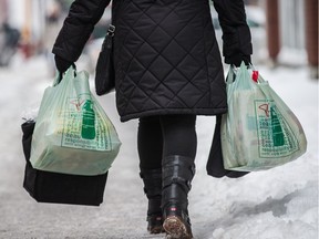A woman carries plastic grocery bags on Tuesday.