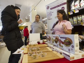 Chantal Bekhor (right) and Emmanuel Castiel, co-founders of Vegetarian Gourmet, watch as shopper Geneviève Guérard samples one of their burgers at a Rachelle Bery store in Town of Mount Royal.