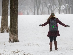 A woman regains her balance as she walks over a patch of ice at Jeanne-Mance park during a moderate snow fall in Montreal on Wednesday, Feb. 24, 2016.