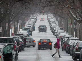 Pedestrians cross the street near the corner of Foucher street and Cremazie boulevard during a light snow fall in Montreal on Wednesday, February 24, 2016. (