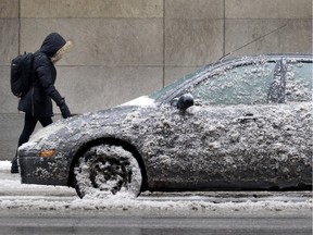 A pedestrian passes an iced over car on Peel St. in Montreal, Feb. 3, 2016.