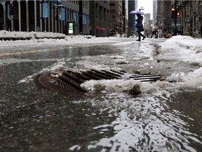 A pedestrian makes her way across de Maisonneuve Blvd. in as rain water puddles around a drain grate on Wednesday February 3, 2016. Montreal has become a no-snow zone, more reminiscent of April than February, Josh Freed writes.