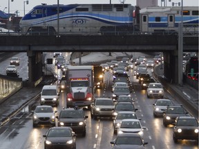 Cars move south on the Décarie Expressway while an AMT commuter train passes over top.