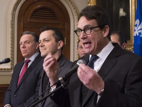Parti Québécois Leader Pierre Karl Péladeau responds to reporters at a news conference, Wednesday, Feb. 24, 2016 at the legislature in Quebec City. Jean Poirier, former Aveos union representative, centre, invited Coalition Avenir Québec Leader François Legault, left, and Péladeau to join him at the news conference.