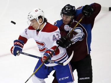 Montreal Canadiens right wing Sven Andrighetto, left, of the Czech Republic, avoids the puck as it flies by as he is tied up by Colorado Avalanche defenceman Tyson Barrie in the first period go an NHL hockey game Wednesday, Feb. 17, 2016, in Denver.