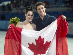Ice dance silver medallists Canada's Tessa Virtue and Scott Moir pose with the Canadian flag during flowers ceremony at the Sochi Winter Olympics Monday, February 17, 2014 in Sochi.