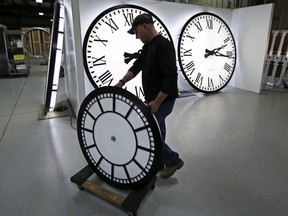 Dan LaMoore wheels a clock away from the test area as it is prepared to be shipped to a Tennessee school at the Electric Time Company in Medfield, Mass., Thursday, March 10, 2016. We will lose an hour of sleep this weekend, but gain an hour of evening light for months ahead, as daylight saving time returns this weekend. The time change officially starts Sunday at 2 a.m. local time.