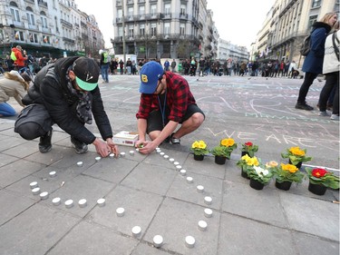 People leave candles and flowers in tribute to victims of triple bomb attacks in front of the stock exchange building in the city center of Brussels on March 22, 2016.