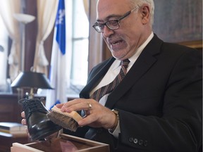 Quebec Finance Minister Carlos Leitao polishes his old shoes as he speaks to reporters on the eve of a budget speech, Wednesday, March 16, 2016 at the Finance Ministry in Quebec City.