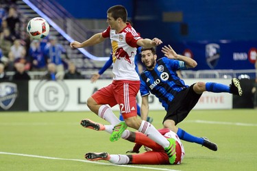 Montreal Impact midfielder Ignacio Piatti, right, falls as he collides with New York Red Bulls defenders Kemar Lawrence, on ground, and Karl Ouimette, left, during the second half of the Impact's home opener at the Olympic Stadium in Montreal on Saturday, March 12, 2016.