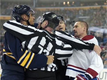 Buffalo Sabres' Evander Kane, left, is restrained by NHL linesman Vaughan Rody (73) as linesman Kiel Murchison, center, holds on to Montreal Canadiens' Tomas Plekanec, right, during the first period of an NHL hockey game, Wednesday, March 16, 2016, in Buffalo, N.Y.  Montreal won 3-2 in overtime.