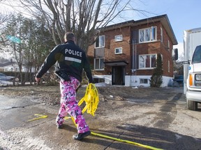 A Montreal police officer walks past a house that was heavily damaged by fire, on Gouin Blvd. West near 2nd Street in Montreal, Monday March 21, 2016.