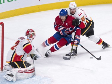 Montreal Canadiens' Max Pacioretty, centre, is held back by Calgary Flames defenceman Tyler Wotherspoon, right, as he drives towards Flames goalie Niklas Backstrom during first-period action Sunday, March 20, 2016, in Montreal.