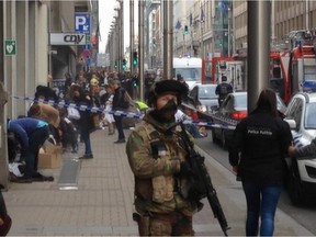 In this image taken from TV an armed member of the security forces stands guard as emergency services  attend the scene after a explosion in a main metro station in Brussels on Tuesday, March 22, 2016. Explosions rocked the Brussels airport and the subway system Tuesday, killing a number of  people and injuring many others just days after the main suspect in the November Paris attacks was arrested in the city, police said. (AP Photo)