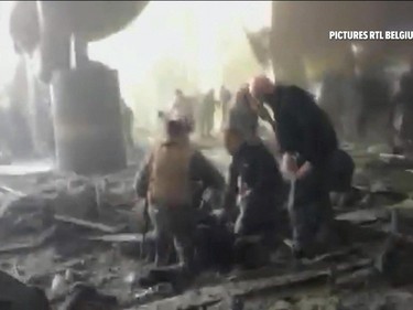 In this still image taken from video from RTL Belgium  people receive treatment in the debris strewn terminal at Brussels Airport, in Brussels after explosions Tuesday, March 22, 2016. Authorities locked down the Belgian capital on Tuesday after explosions rocked the Brussels airport and subway system, killing  a number of people and injuring many more. Belgium raised its terror alert to its highest level, diverting arriving planes and trains and ordering people to stay where they were. Airports across Europe tightened security.  (RTL via AP) BELGIUM OUT TV OUT NO ARCHIVE