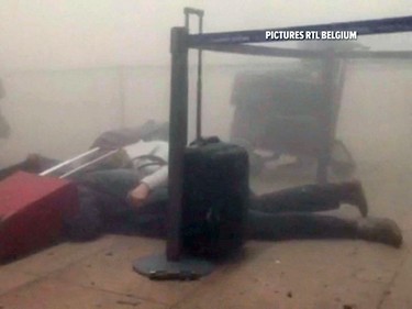 In this still image taken from video from RTL Belgium  unidentified travellers lie on the floor in a smoke filled terminal at Brussels Airport, in Brussels after explosions Tuesday, March 22, 2016.