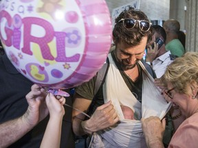 An Israeli father carries his baby born to a surrogate mother in Nepal as he is cheered by relatives at Ben Gurion airport near Tel Aviv on April 28, 2015, following his repatriation from the quake-hit Himalayan nation.