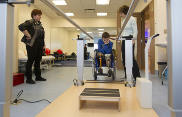 Physiotherapist Rochelle Rein encourages Mykola Nyzhnykovskyi as his mother Alla Nyzhnykovska  looks on as he takes a break in a session on his prosthetic legs at Shriners Hospitals for Children in Montreal Tuesday, March 15, 2016. Mykola lost his legs and an arm in East Ukraine and sustained other serious injuries from an exploding grenade that killed his younger brother. Behind is Lesia Prystupa, an interpreter and aid to  Mykola and his mother.