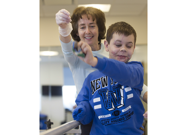 In an exercise to work on balance during a physiotherapy session with physiotherapist Rochelle Rein, Mykola Nyzhnykovskyi snatches a sandbag held by Rein at Shriners Hospitals for Children in Montreal Tuesday, March 15, 2016. Mykola lost his legs and an arm in East Ukraine and sustained other serious injuries from an exploding grenade that killed his younger brother.