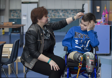 Alla Nyzhnykovska fixes the hair of her son Mykola Nyzhnykovskyi after a session on his prosthetic legs at Shriners Hospitals for Children in Montreal Tuesday, March 15, 2016. Mykola lost his legs and an arm in East Ukraine and sustained other serious injuries from an exploding grenade that killed his younger brother.