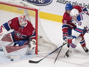 Canadiens goaltender Mike Condon stops New York Rangers' Kevin Hayes (13) as Canadiens' Joel Hanley (71) defends during first period NHL hockey action in Montreal, Saturday, March 26, 2016.