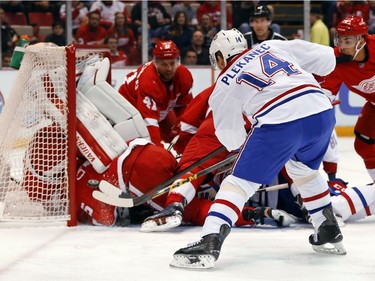 Montreal Canadiens center Tomas Plekanec (14) shoots on Detroit Red Wings goalie Petr Mrazek, upside down in the goal, in the first period of an NHL hockey game, Thursday, March 24, 2016 in Detroit.