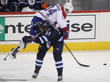 Dustin Byfuglien of the Winnipeg Jets ties up Michael McCarron of the Montreal Canadiens in first period action in an NHL game at the MTS Centre on March 5, 2016, in Winnipeg.