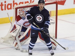 Mike Condon of the Montreal Canadiens looks around Marko Dano of the Winnipeg Jets in third period action on Saturday in Winnipeg.