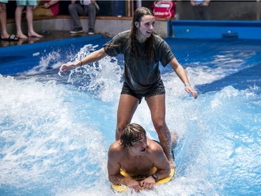 Charlotte Sarrazin, top, and pro surfer Sean "Poopies" Mcinerney, bottom, tandem-ride an artificial wave at Oasis Surf on Friday, March 25, 2016, in Brossard.