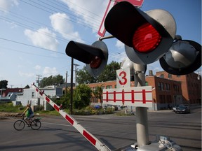A train crossing sign flashes as a cyclist crosses the train tracks before a train crossing on St. Ambroise street near the corner of St. Augustine street close to homes in the neighbourhood of Saint-Henri in Montreal in 2013.