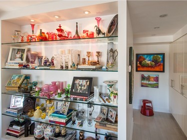 A view of the glass shelvings with decorations, including 1800s cranberry glass, top, and paintings created by Tamra Rubin, right, on display at her home in Côte St-Luc. (Dario Ayala / Montreal Gazette)